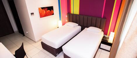 A hotel room with two single beds, a desk, and a chair.