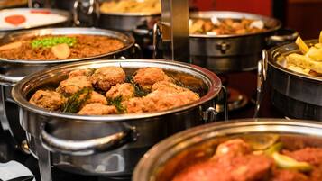 A buffet with various dishes, including meatballs and a red sauce dish.