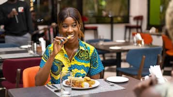 A person seated at a table with a plate of food, a glass of water, and a napkin.