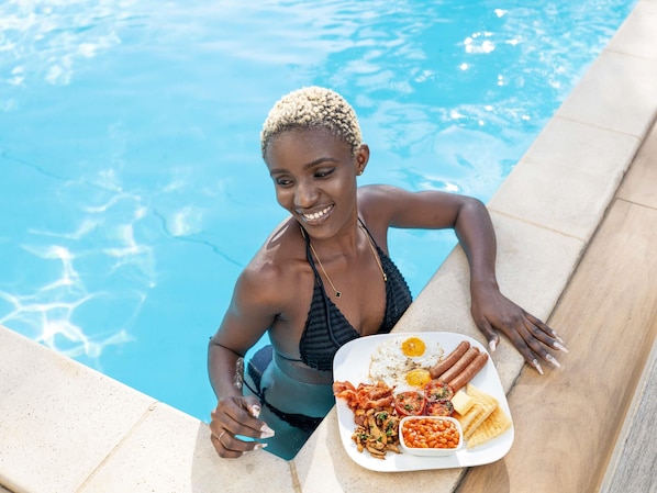 A person by a poolside with a plate of food.