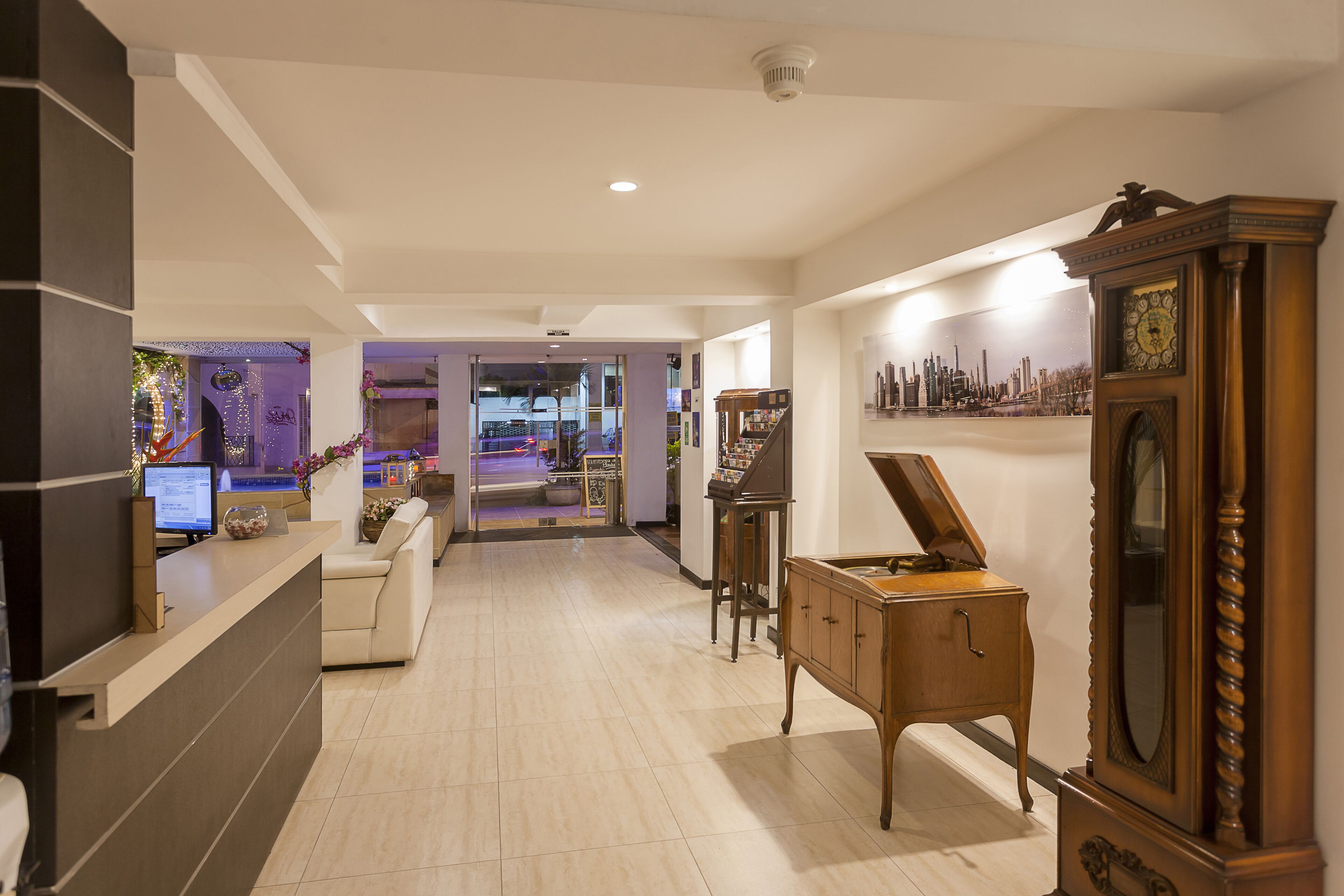 A spacious lobby with a reception desk, a piano, and a large mirror.