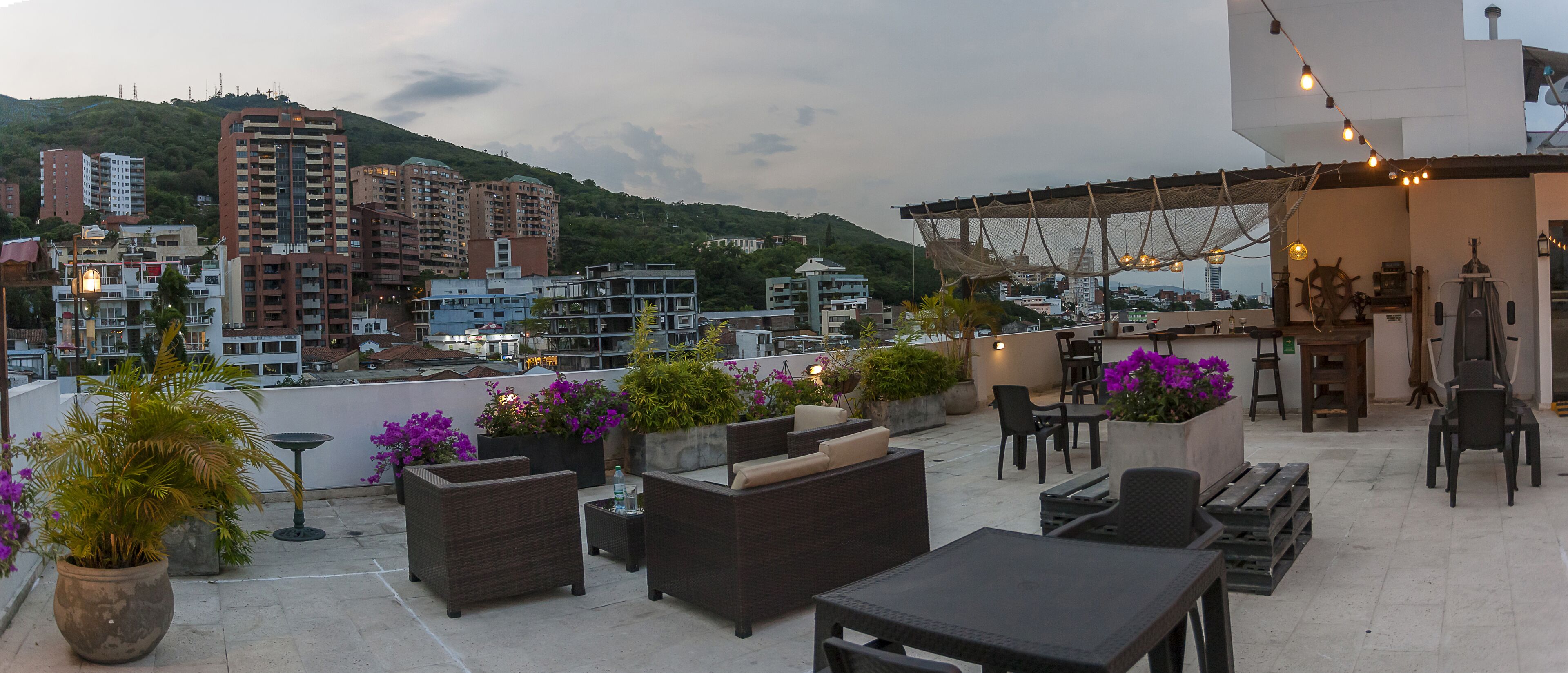 A rooftop terrace with outdoor seating, potted plants, and city views.