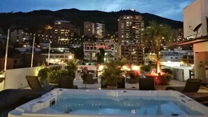 A rooftop pool area with a hot tub, lounge chairs, and potted plants. - Aqua Granada Hotel (Cali)