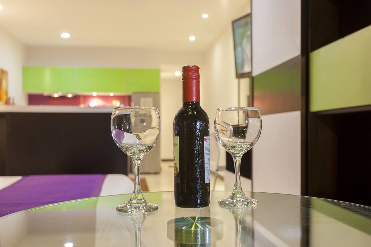 Una mesa de vidrio con una botella de vino y dos copas de vino.