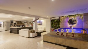 A modern hotel lobby with a reception desk, a seating area, and a decorative wall with the words "LOVE CALI". - Aqua Granada Hotel (Cali)