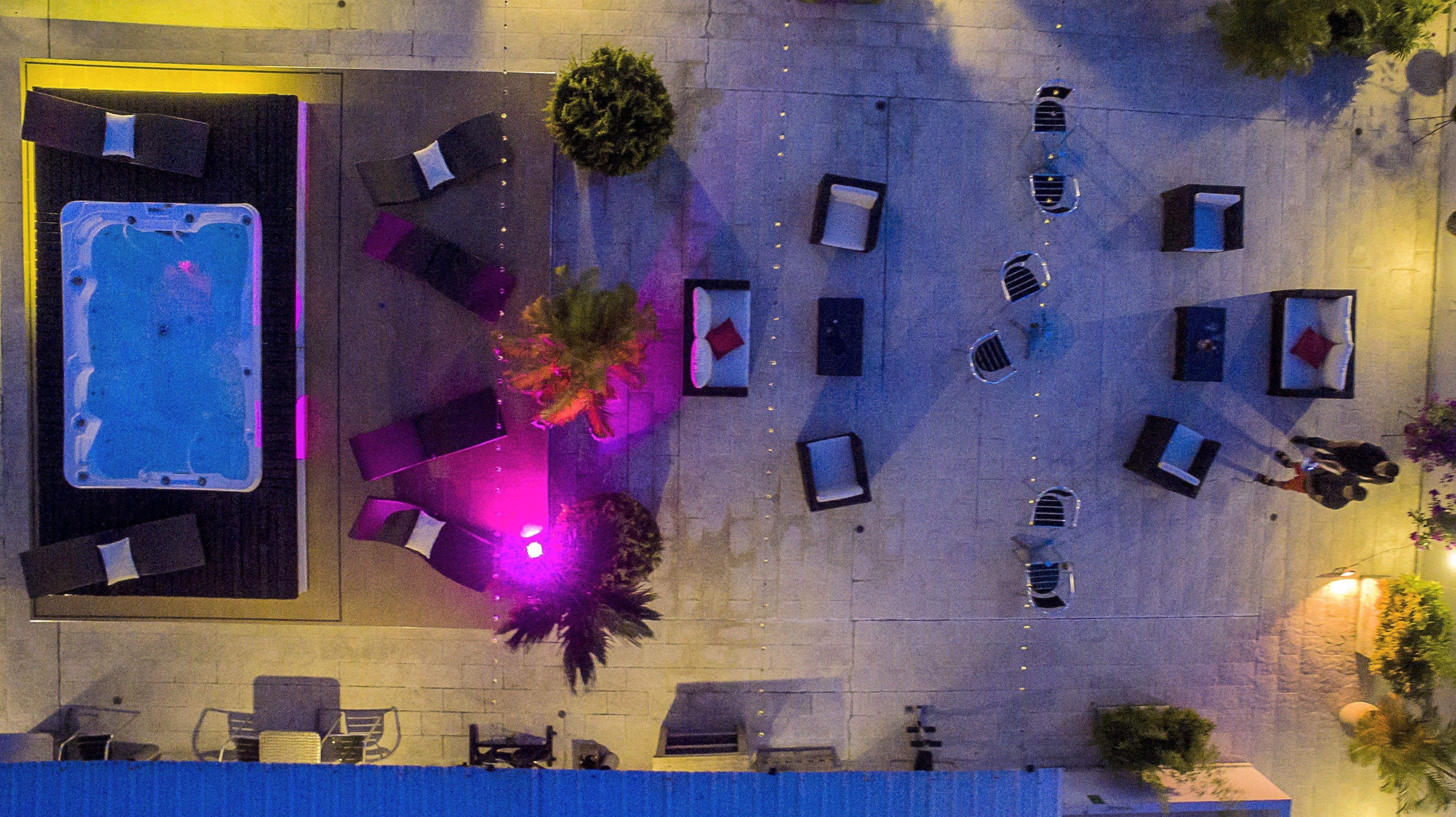 Vue aérienne d’un espace piscine sur le toit, avec plusieurs chaises longues et un jacuzzi.
