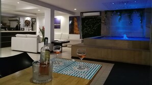 A modern living room with a dining area, a white sofa, a coffee table, and a glass of wine. - Aqua Granada Hotel (Cali)