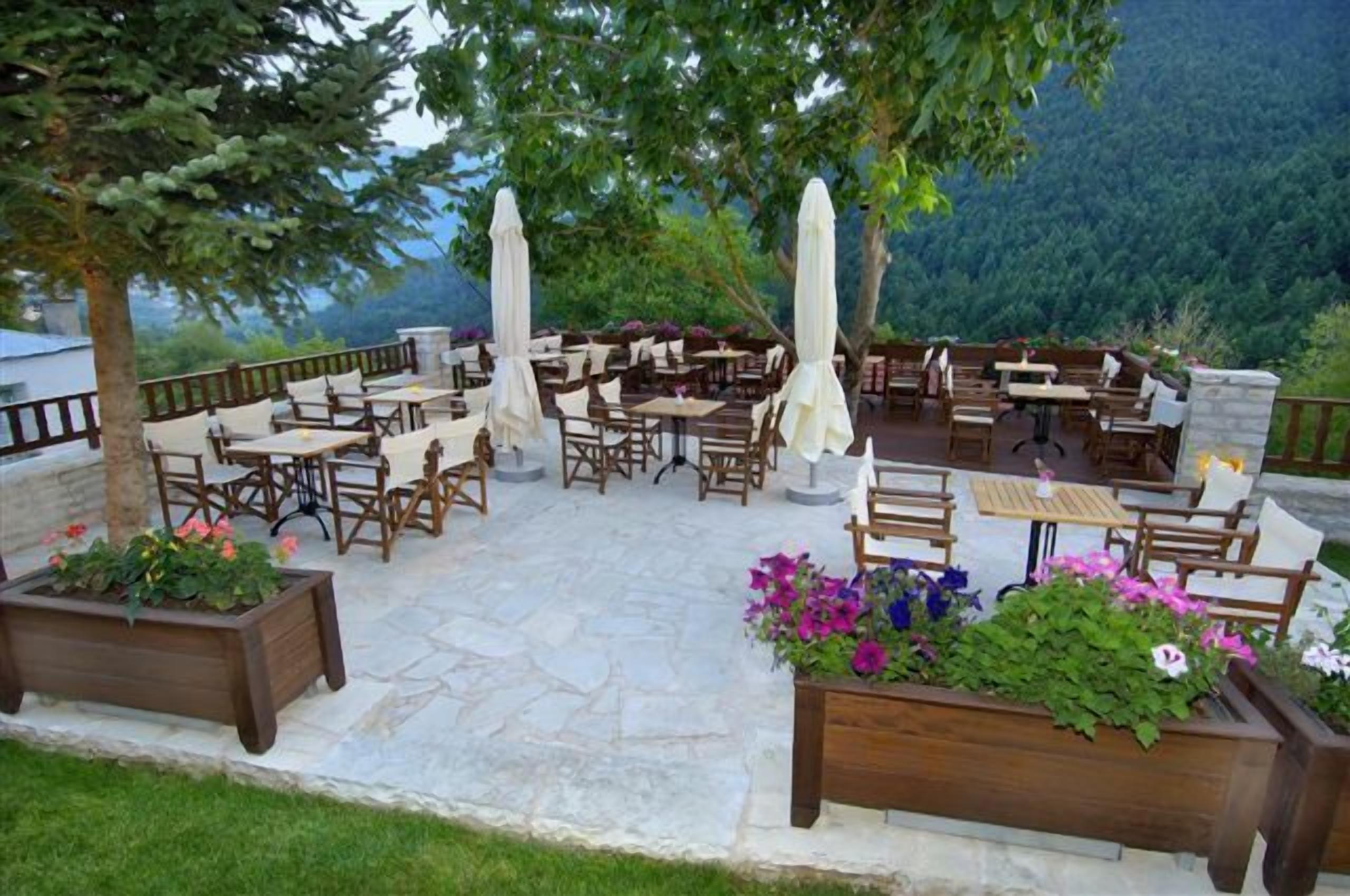 An outdoor patio with wooden furniture, stone flooring, and flower planters.