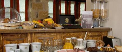 Un bufé de desayuno con diversas opciones de comida, como frutas, pan y bebidas.