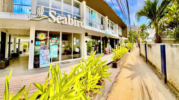 Seabird hotel med en moderne facade, store vinduer og et synligt udendørs opholdsområde.