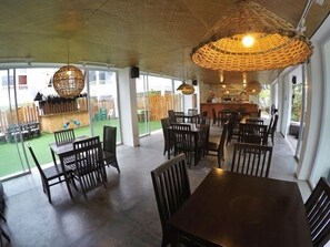 A restaurant with a patio area, tables, chairs, and hanging wicker lamps. - Seabird International Resort (Boracay Island)