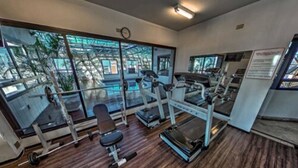 A gym with exercise equipment, large windows, and a wooden floor. - Hotel Massis (São Paulo)
