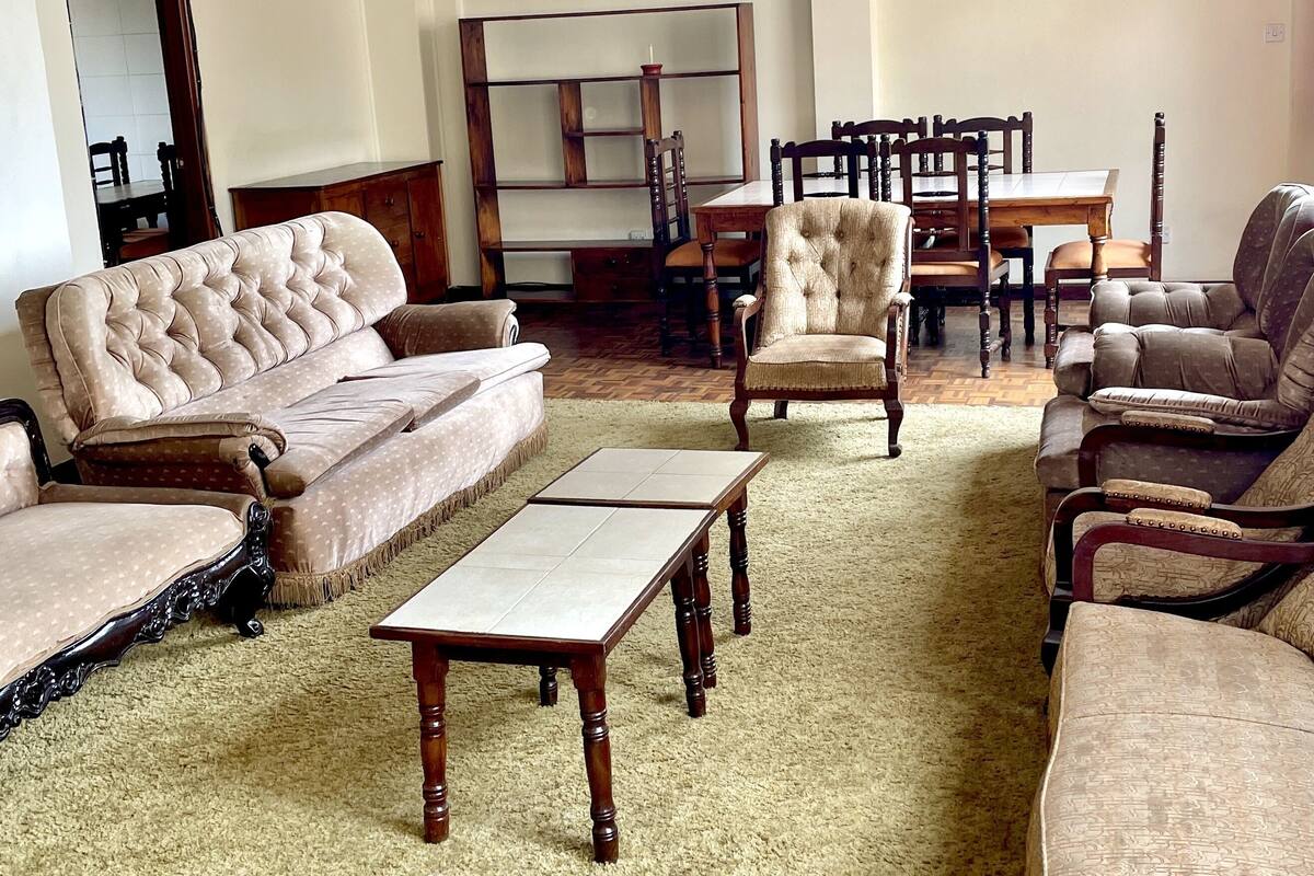 Un salón espacioso con un sofá grande, sillones, una mesa de centro y una zona de comedor con mesa y sillas.