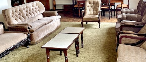Un salon spacieux comprenant un grand canapé, des fauteuils, une table basse et un coin repas avec une table et des chaises.