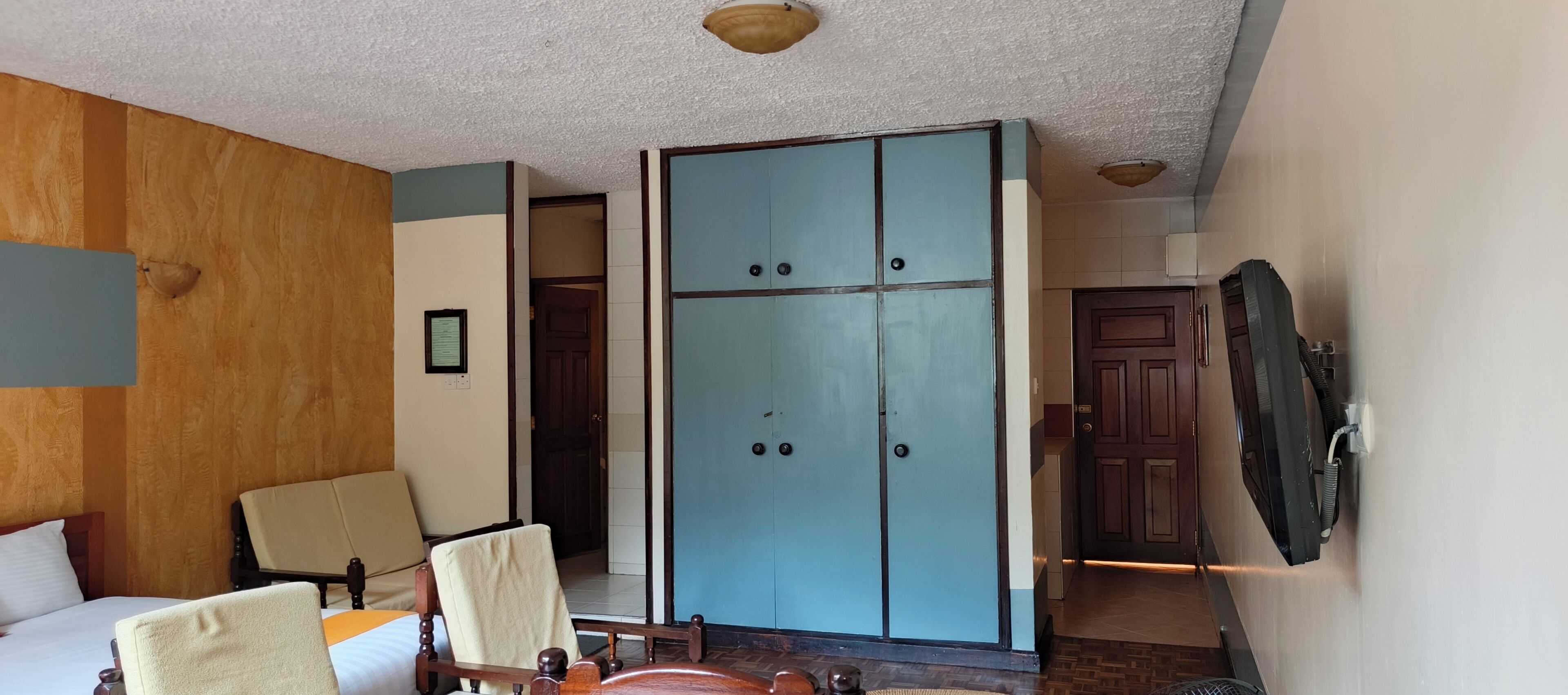 Une chambre d’hôtel avec un lit, une chaise, une armoire et un téléviseur.