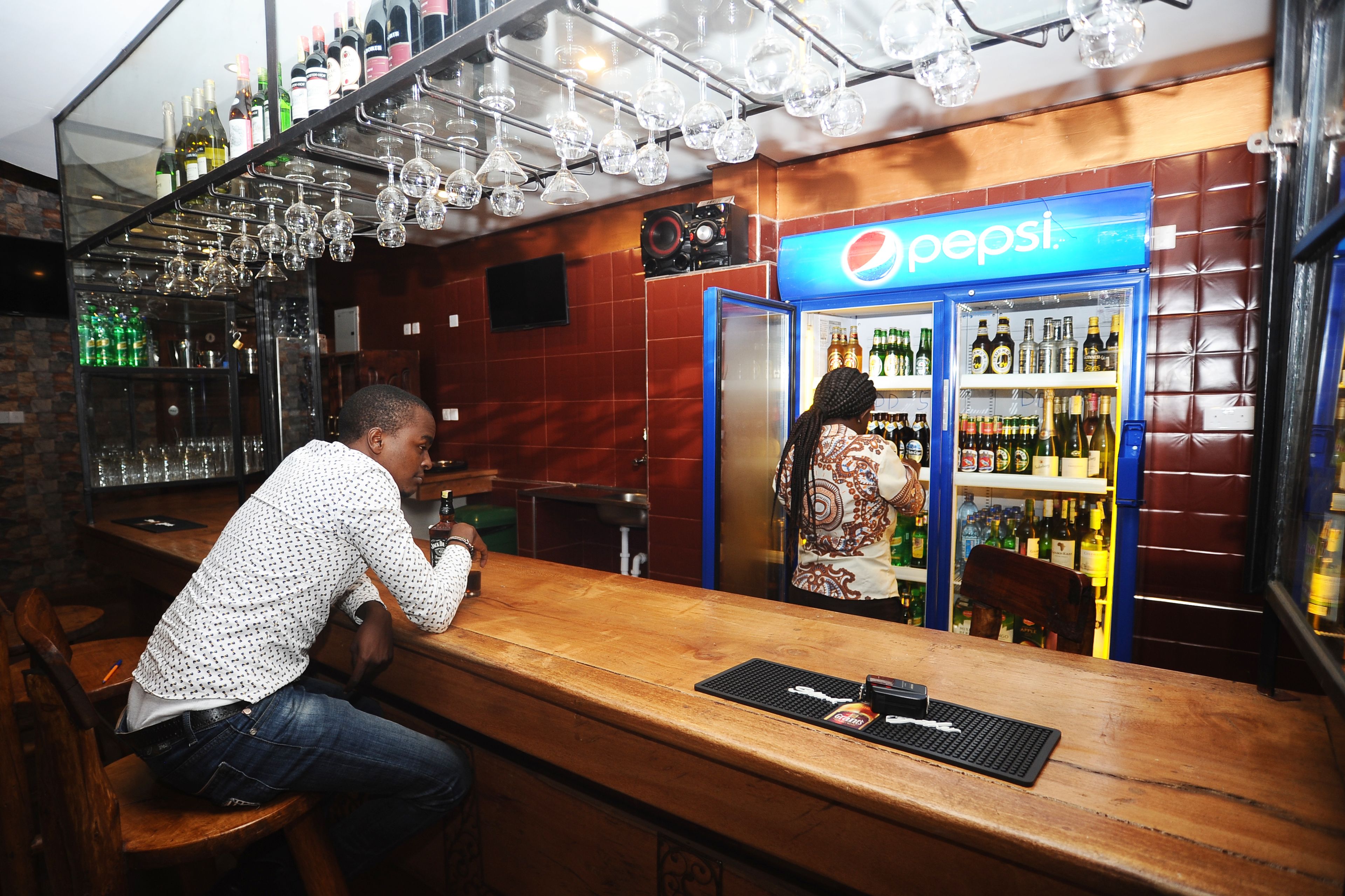 En bar med ett kylskåp fullt av Pepsi, en bartender och en kund.