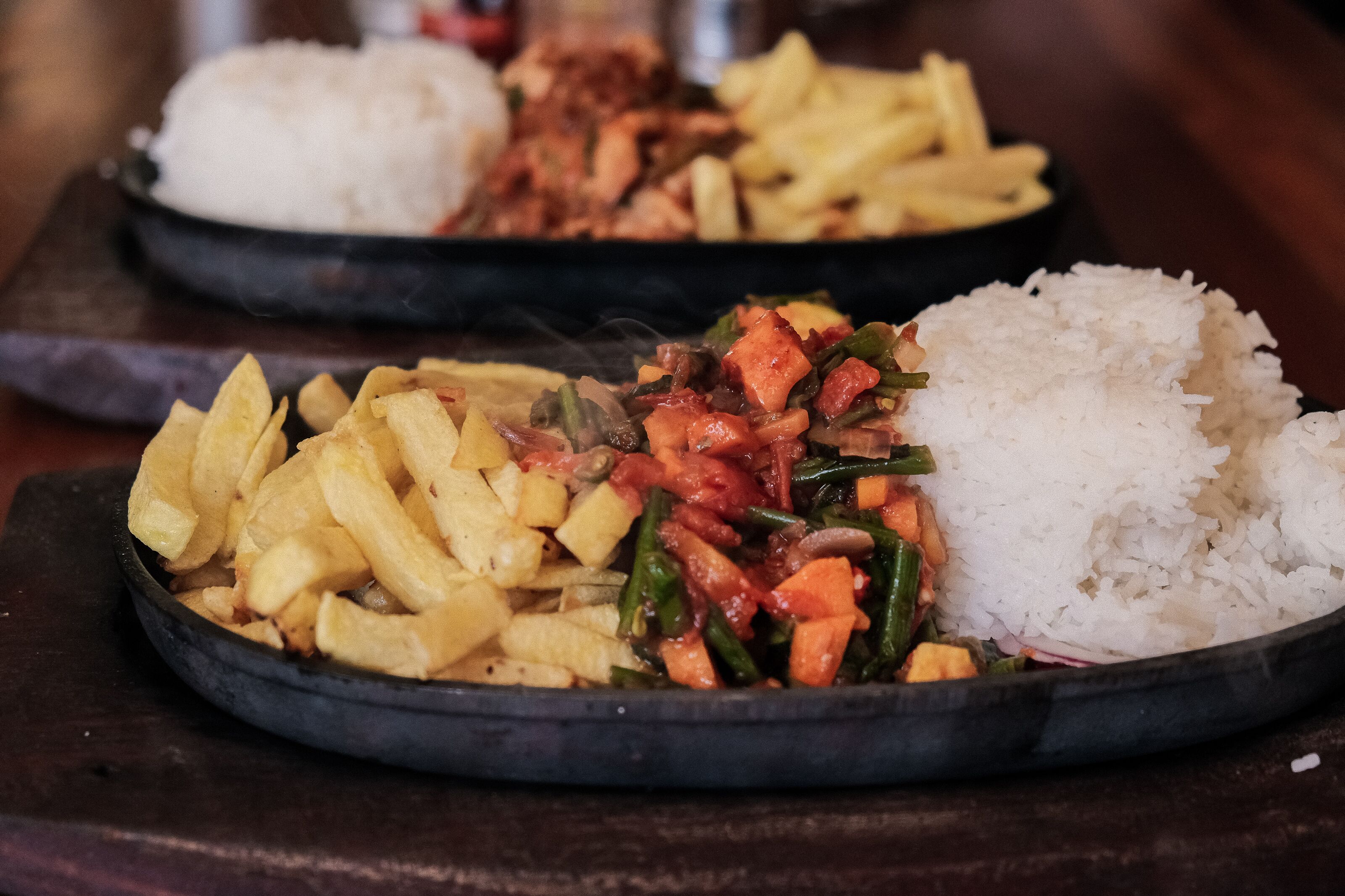 Dos platos de comida con arroz y patatas fritas.