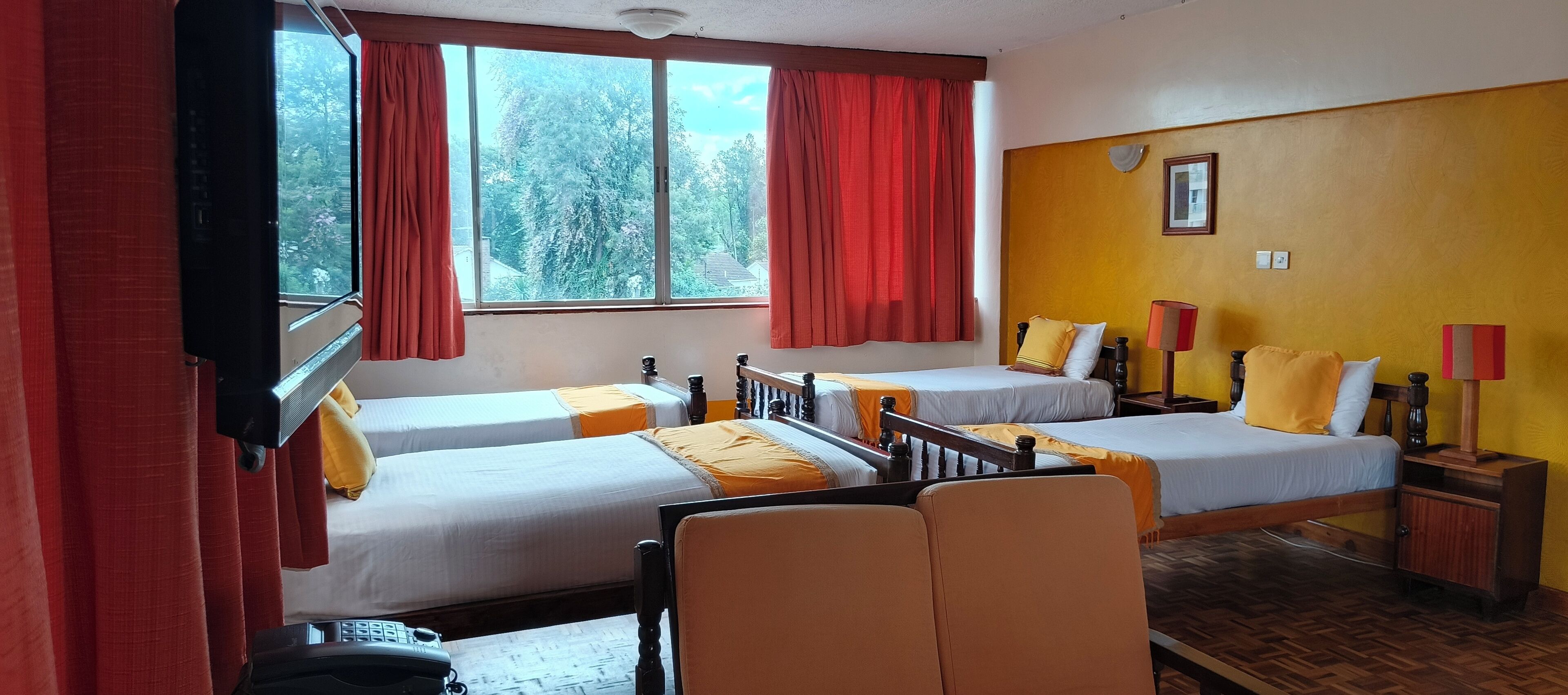 A hotel room with two beds, a wooden chair, a desk, and a window with curtains.