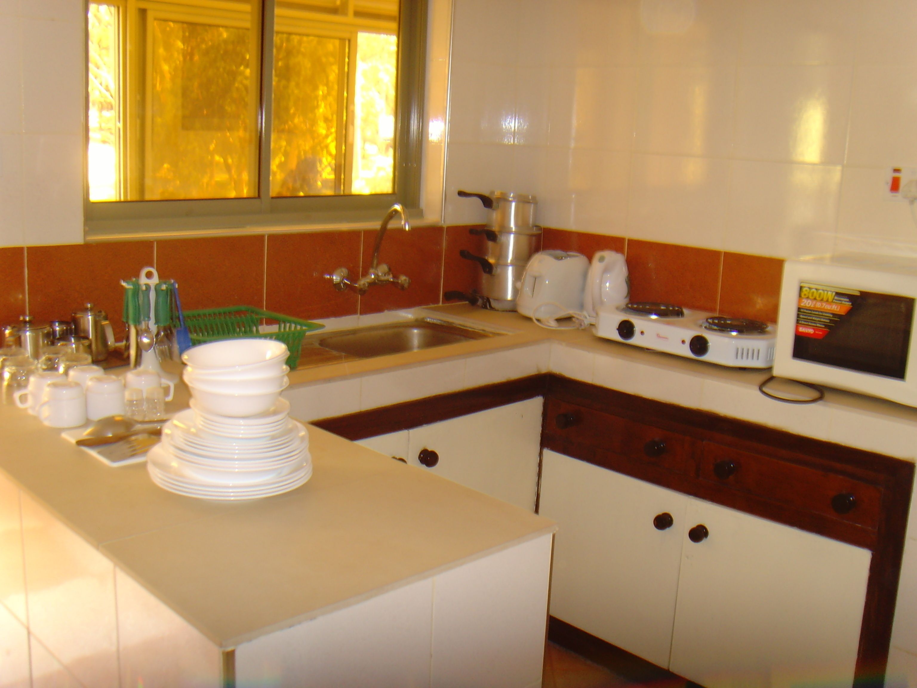 A kitchen with white cabinets, a sink, a stove, and a window with blinds.