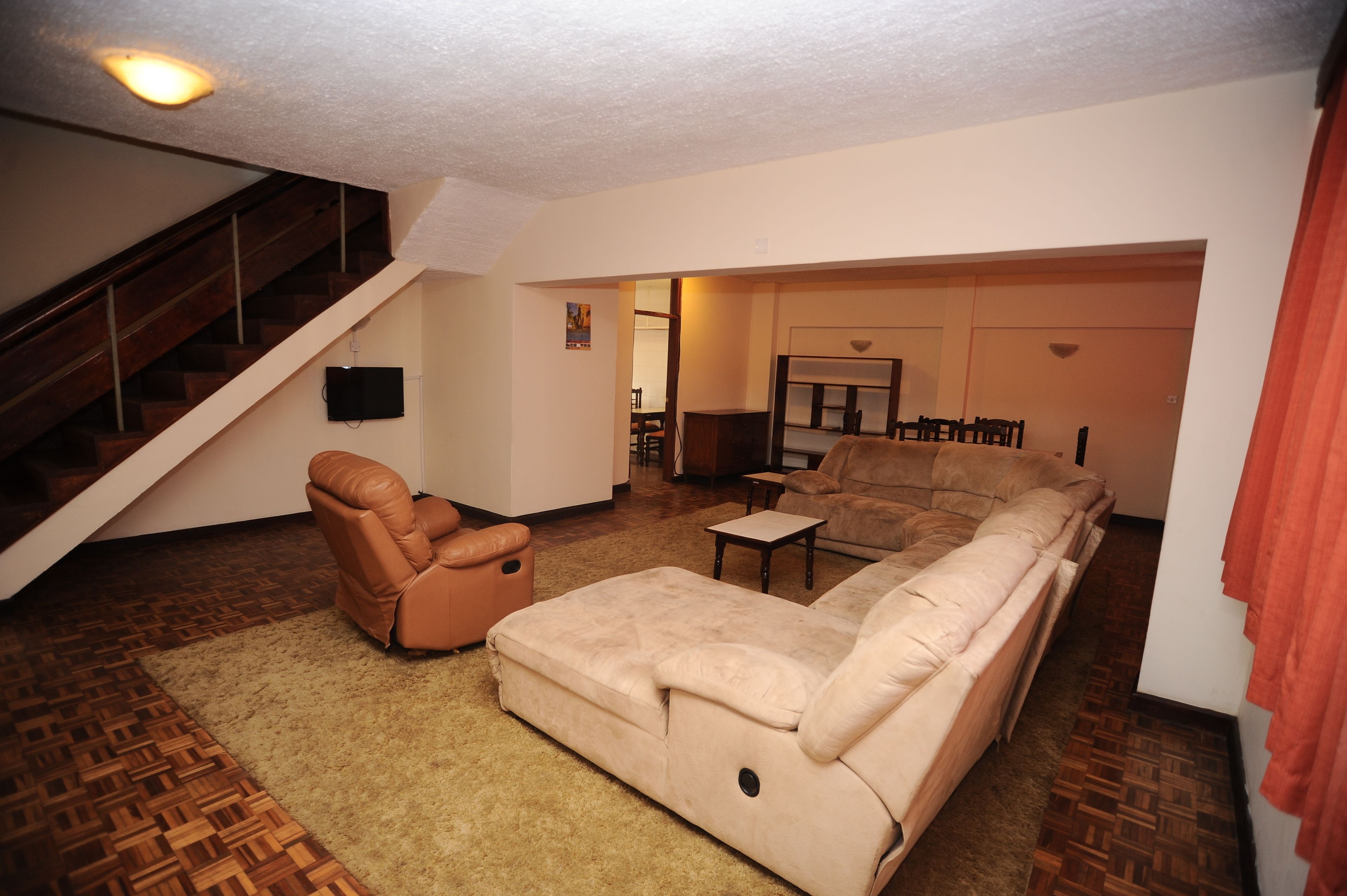 Ein Wohnzimmer mit einer Couch, einem Sessel und einem kleinen Tisch. Eine Treppe führt in einen anderen Raum.