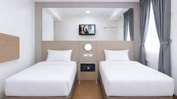 Una camera d'albergo con due letti, una televisione a parete e una finestra con tende.