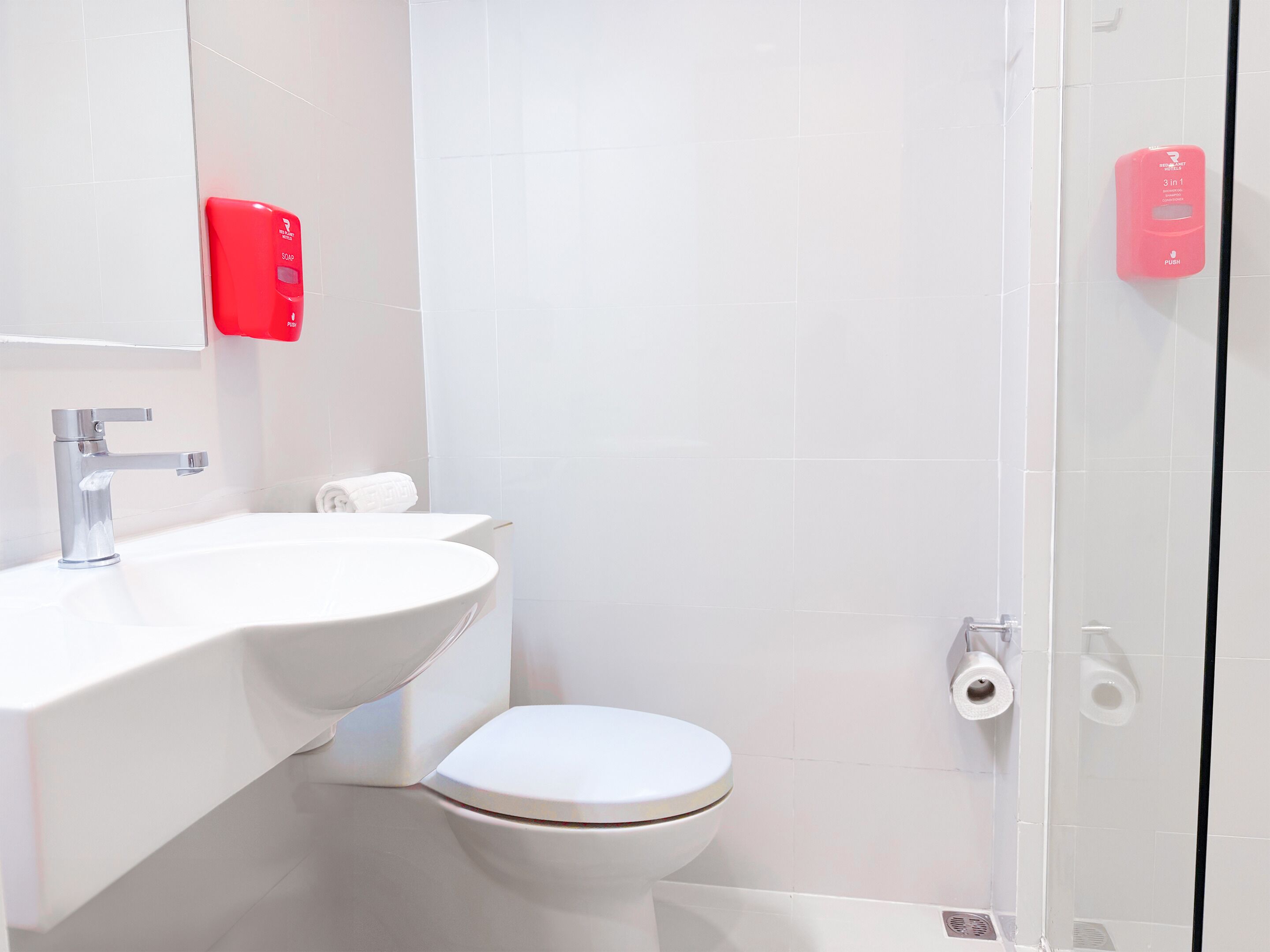 Un baño moderno con un lavamanos blanco, un inodoro y una cabina de ducha de vidrio.