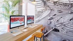 Una oficina moderna con dos monitores, un escritorio de madera y vistas a una calle de la ciudad a través de amplios ventanales.