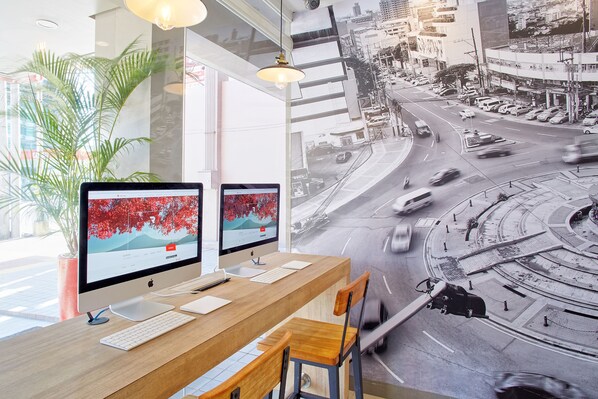 A modern office with two monitors, a wooden desk, and a view of a city street through large windows. - Red Planet Quezon City Timog (Quezon City)