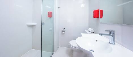 A modern bathroom with a glass shower enclosure, a white sink, and a toilet.