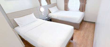 A hotel room with two beds, a flat-screen TV, a mirror, and a window with curtains.