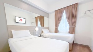 Habitación de hotel con dos camas, un espejo, un televisor y una ventana con cortinas.