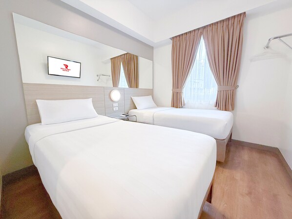 Habitación de hotel con dos camas, un espejo, un televisor y una ventana con cortinas.