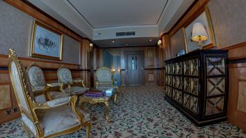 A room with ornate furniture, including a gold and white chair, a matching table, and a cabinet with glass doors.