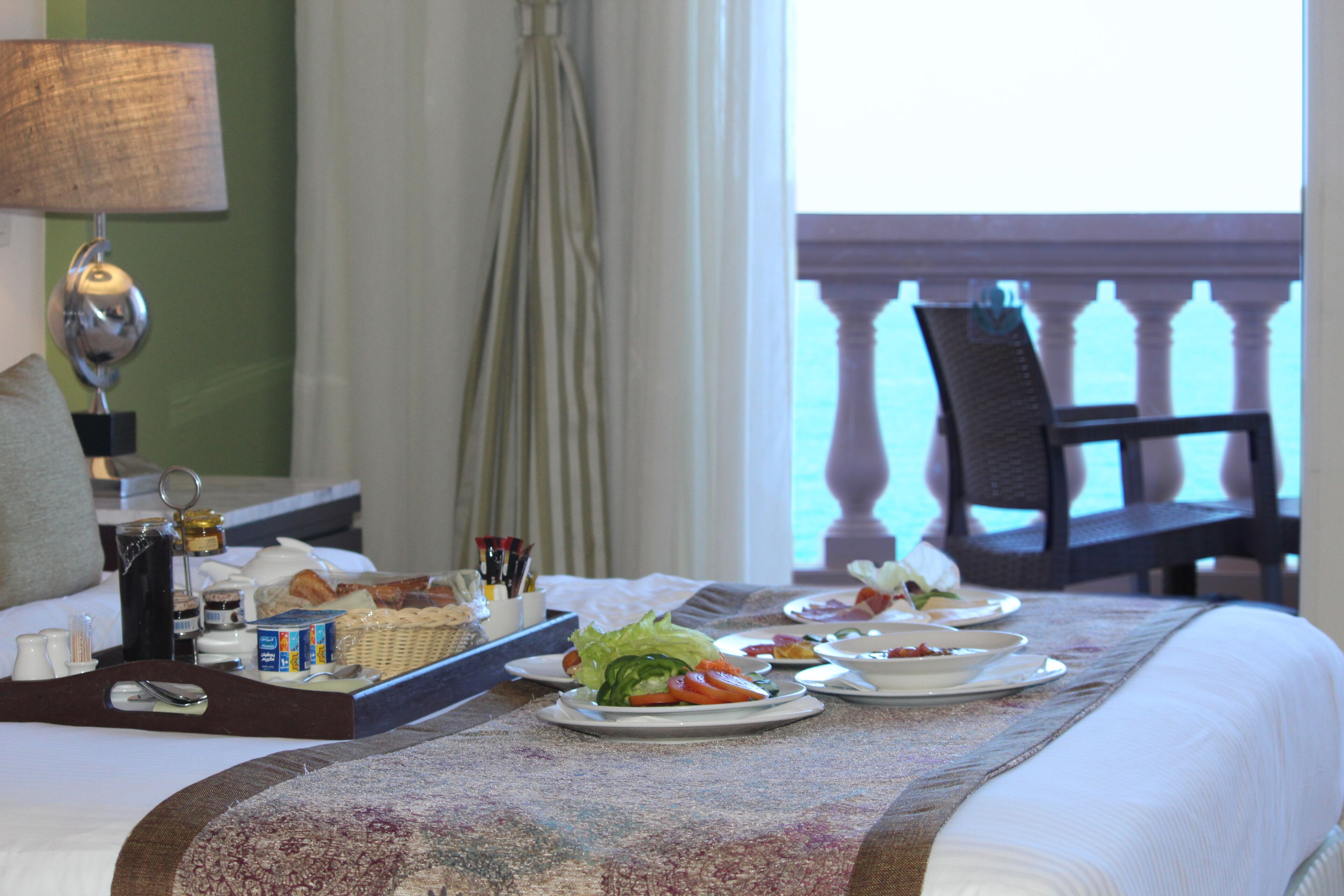 A neatly arranged breakfast buffet on a hotel bed with a view of the balcony.