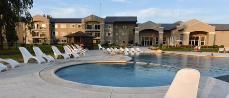 A swimming pool area with lounge chairs and a building in the background.