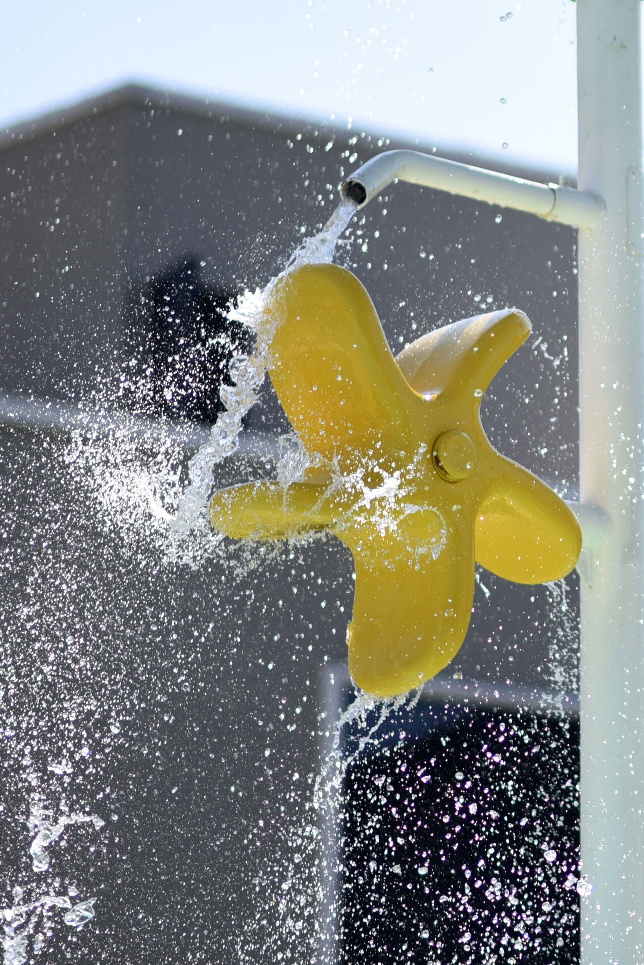 A yellow object being rinsed under a water stream.