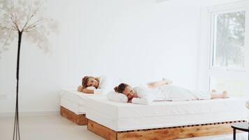 Un dormitorio con dos camas, un ventanal grande y una lámpara de pie alta.