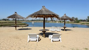 A beach with thatched umbrellas and white lounge chairs. - Howard Johnson by Wyndham Ezeiza Convention Center (Tristan Suarez)