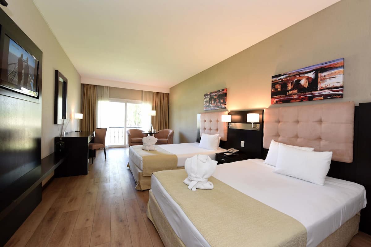 Ein Hotelzimmer mit zwei Betten, einem Schreibtisch, einem Stuhl und einem Fernseher.