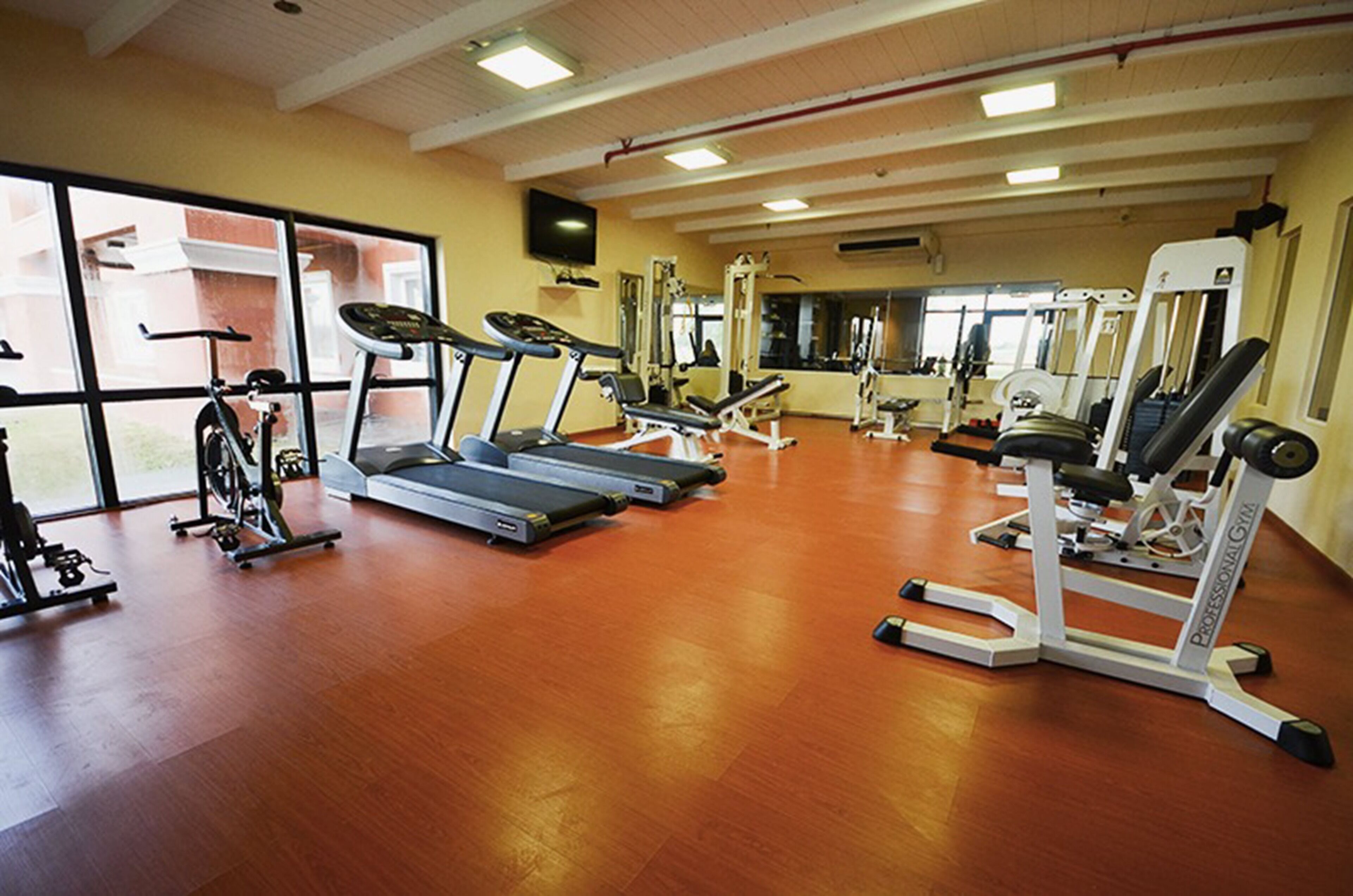 Une salle de sport équipée de tapis de course, d’appareils de musculation et d’un mur entièrement recouvert de miroirs.