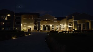A hotel entrance with a covered walkway, multiple windows, and outdoor seating. - Howard Johnson by Wyndham Ezeiza Convention Center (Tristan Suarez)