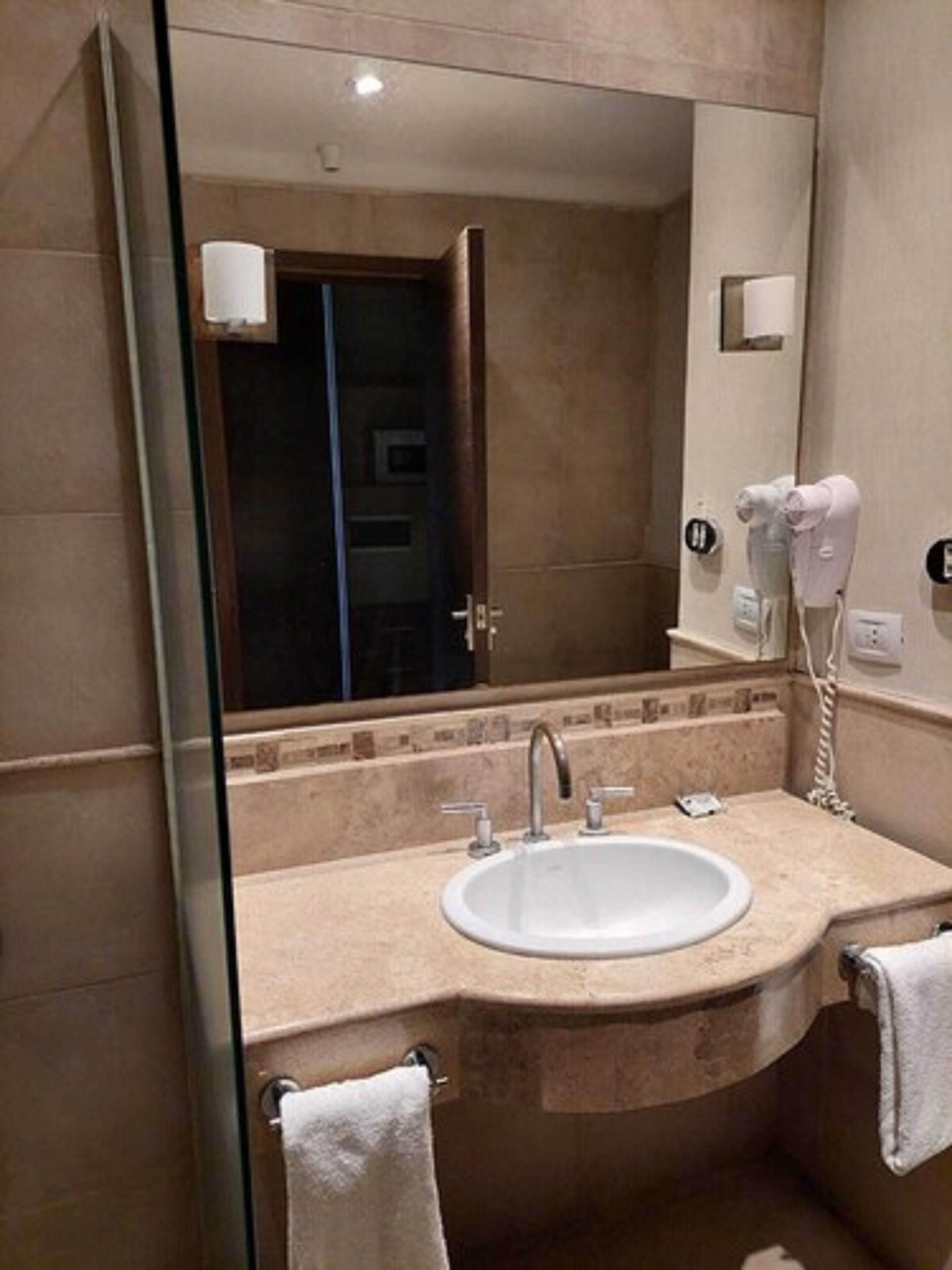 A bathroom with a sink, mirror, and hairdryer.