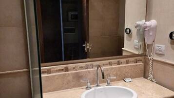A bathroom with a sink, mirror, and hairdryer.
