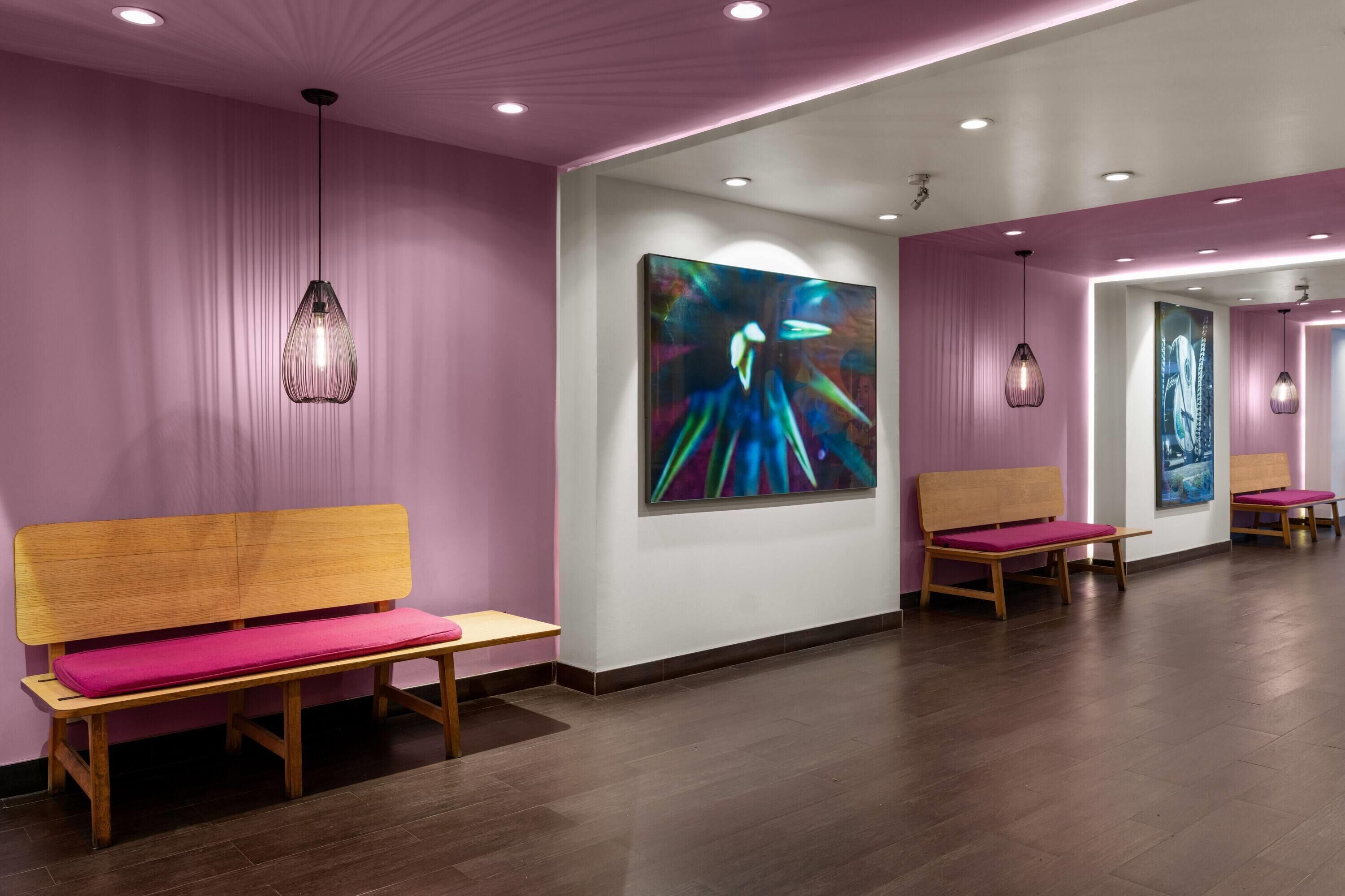 Un interior moderno con bancos de madera, un cuadro abstracto grande e iluminación colgante.