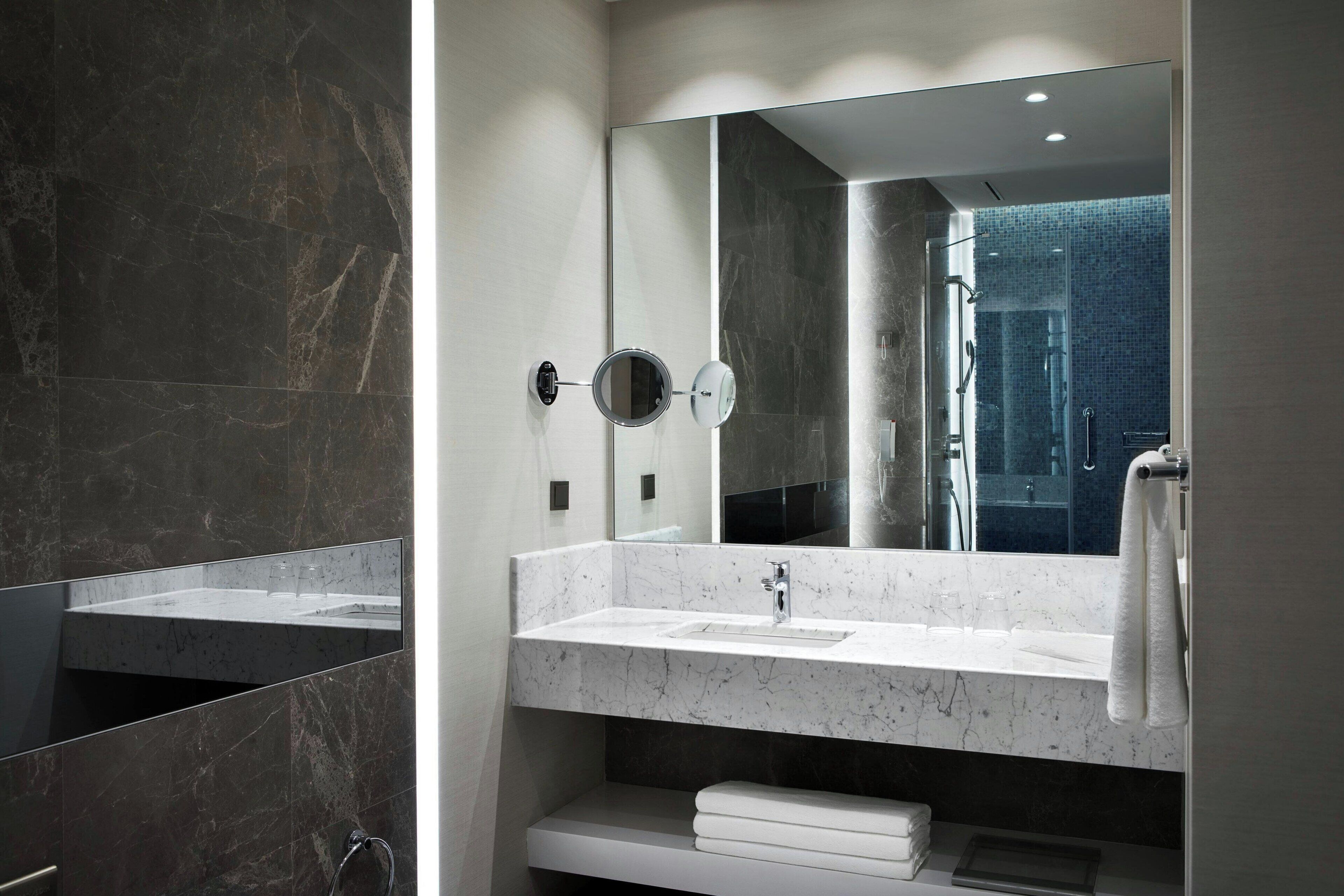 Un baño moderno con un espejo grande, un lavabo y una zona de ducha.