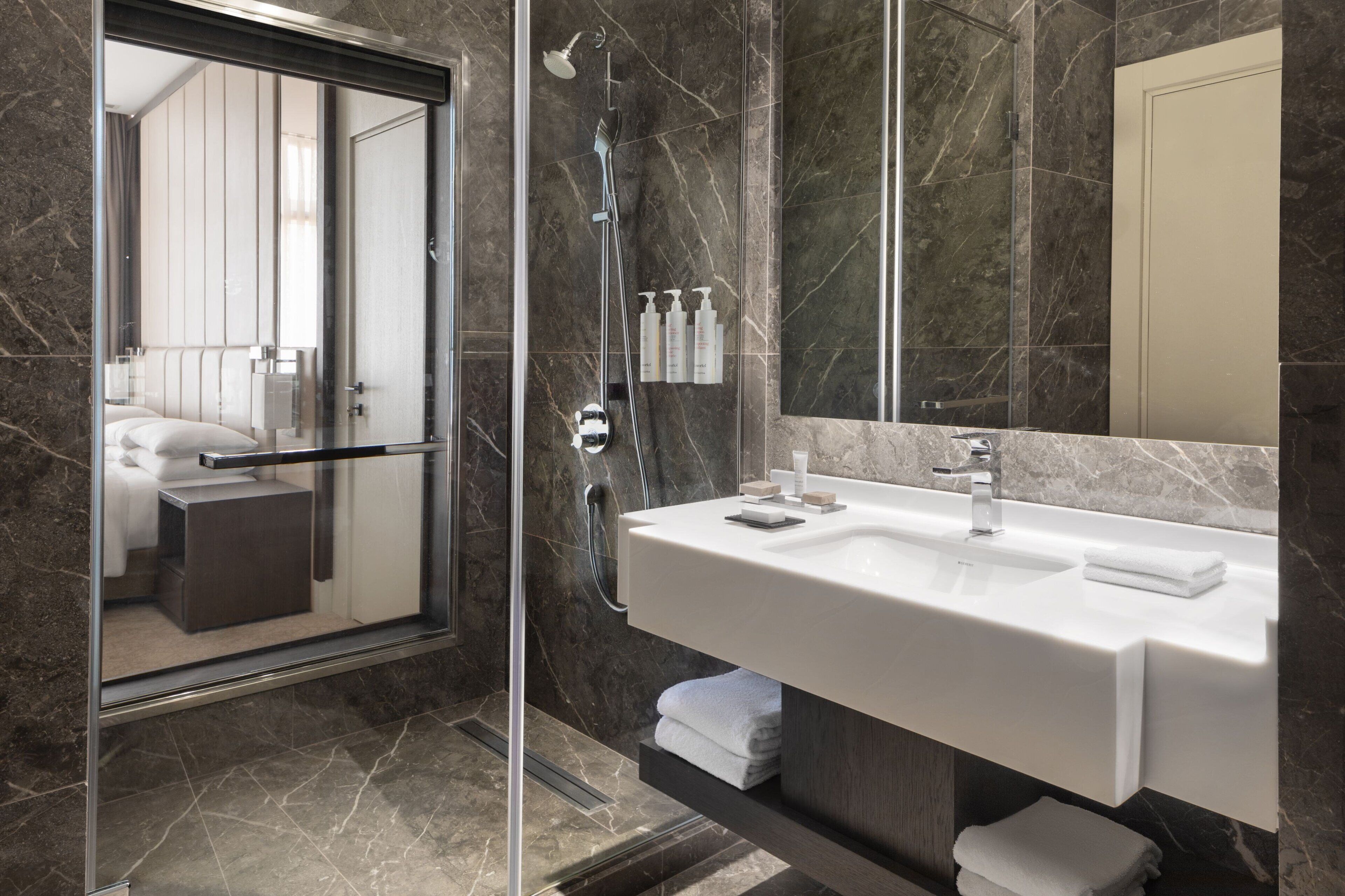A modern bathroom with a glass-enclosed shower, a double sink vanity, and a large mirror.
