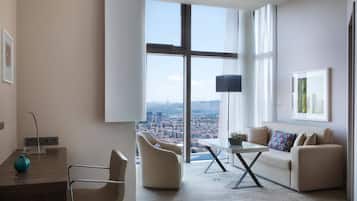Una sala de estar moderna con un ventanal grande, un sofá, una mesa de centro y un escritorio con una lámpara.