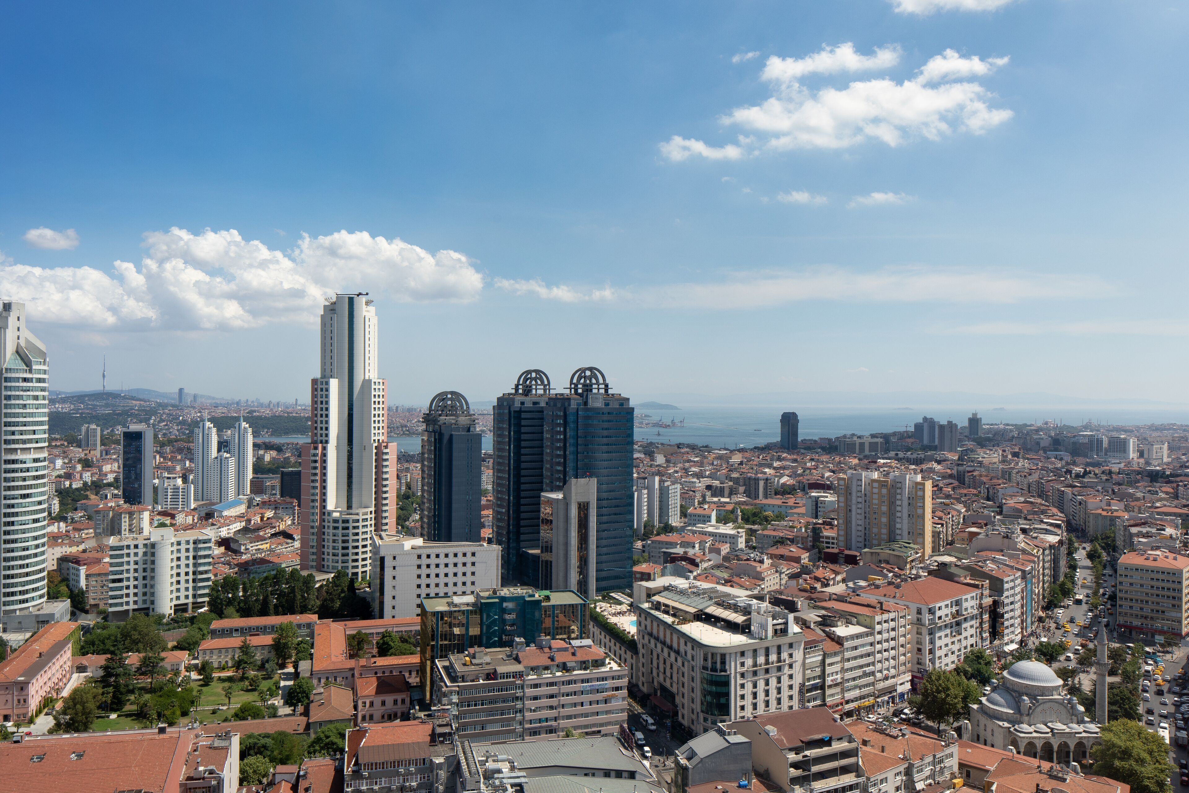 A cityscape with modern high-rise buildings, a mix of architectural styles, and a clear blue sky.