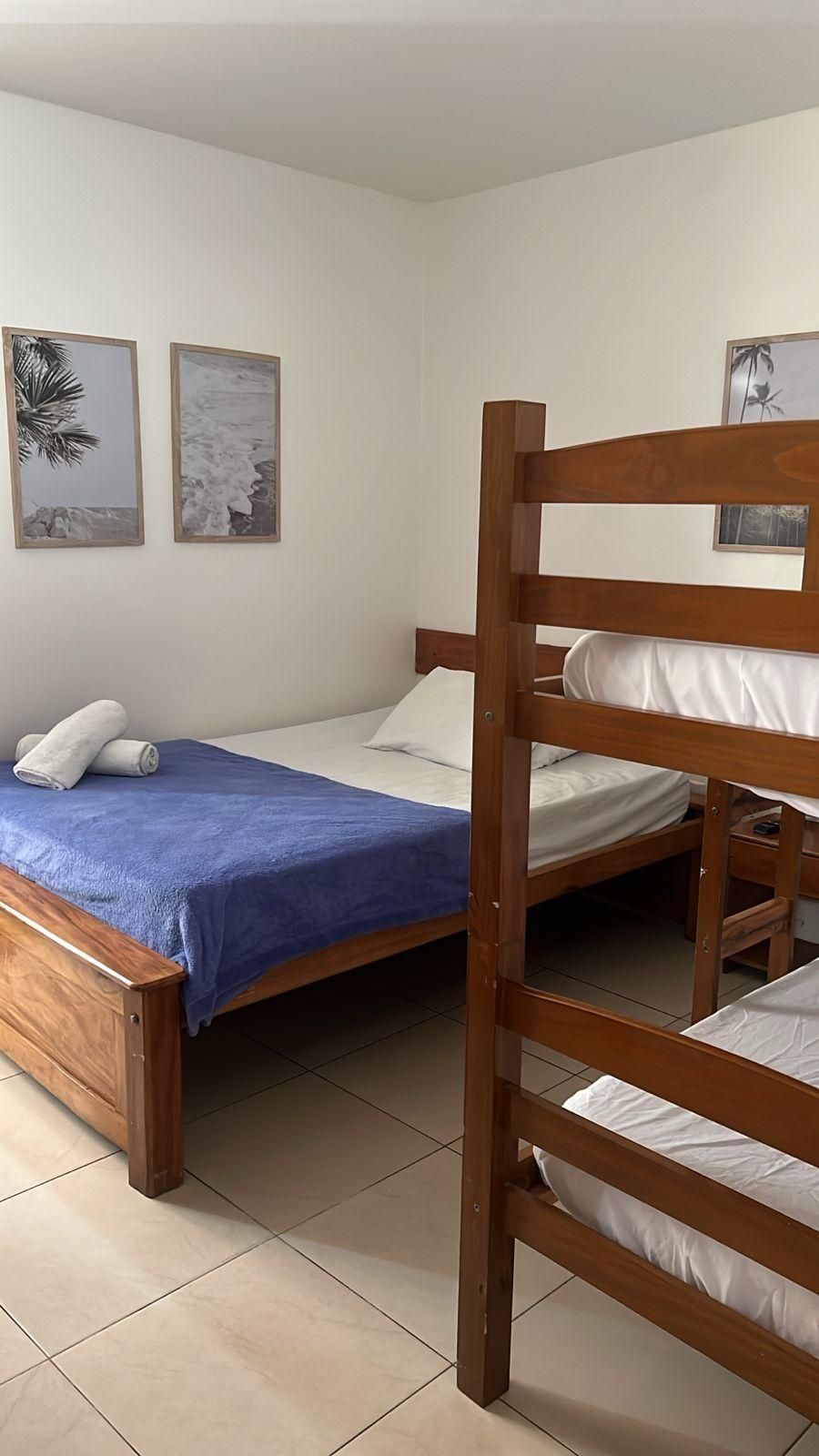 Une chambre avec un lit superposé, un lit simple et deux tableaux encadrés au mur.