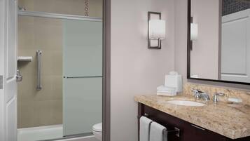 A modern bathroom with a glass shower enclosure, a white sink with a marble countertop, and a large mirror.